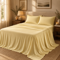 Butter yellow ice silk bedding styled in a warm, calming bedroom with natural wood, soft candlelight and neutral décor.