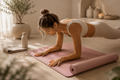 Woman stretching on a black non-slip yoga mat in a calm neutral home studio, suitable for yoga, Pilates and home workouts.