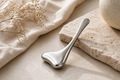 Stainless steel cooling facial massager styled on neutral stone with soft linen for a calming at-home skincare ritual.
