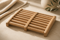 Natural wooden foot massager with textured rollers styled in a warm, calming spa setting.