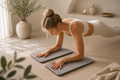 Woman using stone grey cushioned yoga knee support pads during a forearm plank in a warm, minimalist home yoga space